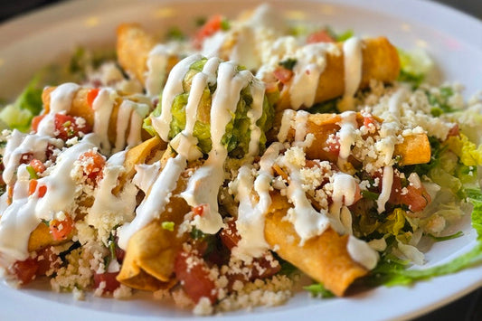 A Plate of Flautas Sprinkled with Cheese, Drizzled with Sour Cream, and Topped with a Dollop of Guacamole