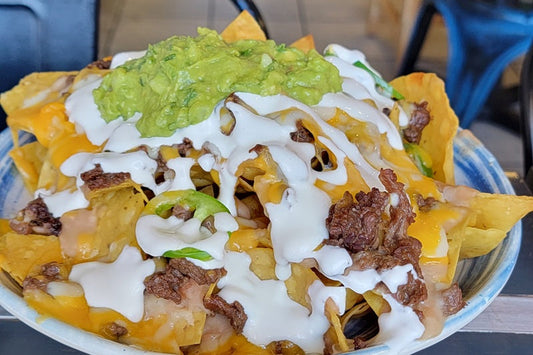 Best Restaurant in Orange County Close Up of Tortilla Chips Covered in Cheese, Sour Cream, and Guacamole on a Plate