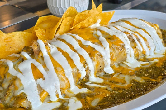 Best Restaurant in South Orange County a Burrito Covered in Green Salsa and Cheese Drizzled with Crema on a Plate with Tortilla Chips